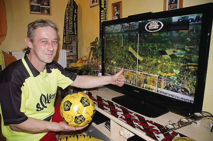 Jochen Pohl ist durch und durch BVB-Fan. In der Dortmunder Südkurve, die auf dem Bildschirm zu sehen ist, stand der Laufer schon selbst. Dort holte er sich den Borussia-Virus. Foto: Scholz