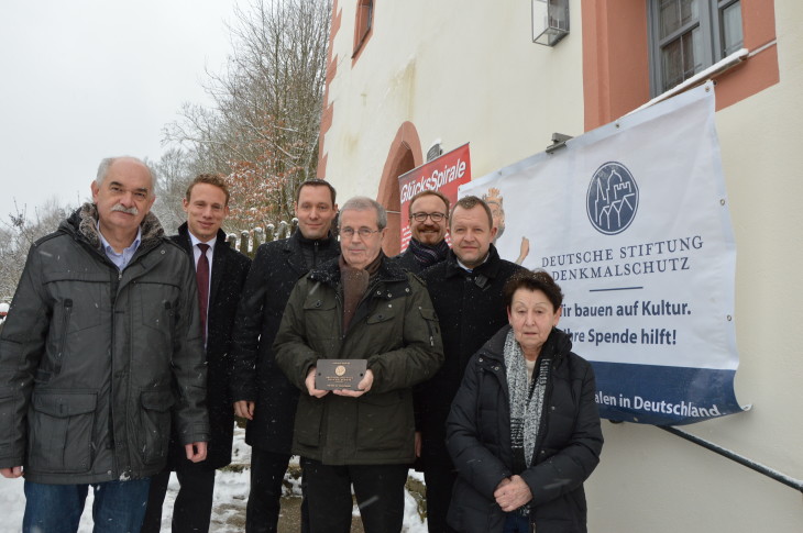 Die Bronzetafel, die Georg Maul vom Verschönerungsverein (Mitte) in Händen hält, erinnert an einen der Hauptsponsoren der Burgsanierung: die Stiftung Denkmalschutz mit der „GlücksSpirale“. Ebenfalls auf dem Bild: Lothar Grimm von der Stiftung Denkmalschutz (links), Stefan Luger von Lotto Bayern (Zweiter v. links), Landrat Armin Kroder (Dritter v. links), Otfried Bürger von der Sparkasse (Dritter v. rechts), Bürgermeister Klaus Albrecht (Zweiter v. rechts) und Gertraud Maul (rechts). Foto: M. Scholz