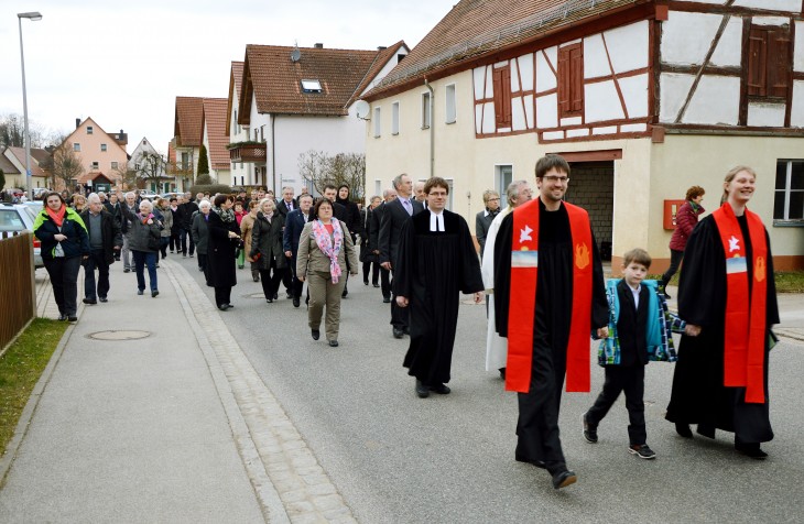 Martin und Ann-Sophie Hoepfner mit ihrem Sohn folgen dem Posaunenchor (nicht im Bild) durchs Dorf. Dahinter die Pfarrer Tristan Schuh (Entenberg) und Hermann Plank (Leinburg-Engelthal; kath.) sowie ein langer Zug mit Gemeindemitgliedern. Foto: M. Scholz