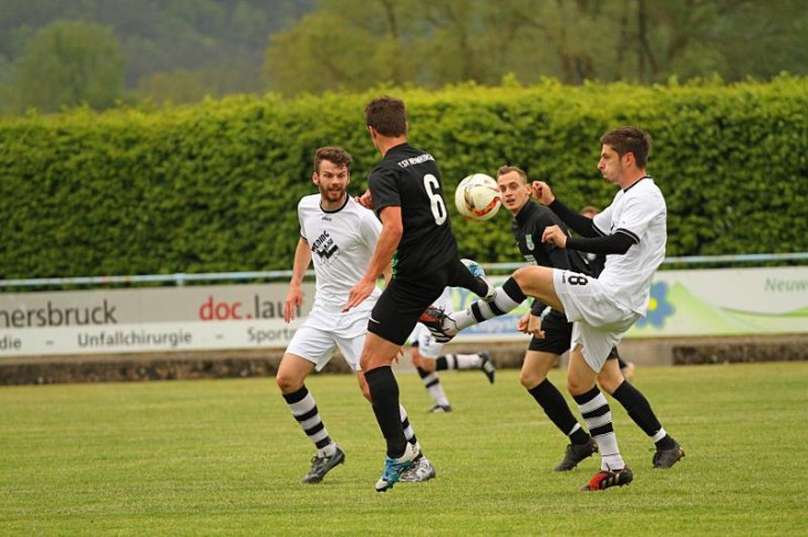 Julian Schneider (links, in Weiß) vom FC Hersbruck beobachtet, wie sein Mannschaftskollege Hannes Herrmann vor dem Neunkirchener Patrick Schütz (6) an den Ball kommt. Foto:  J. Ruppert