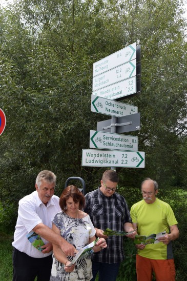 Bürgermeister Konrad Rupprecht, Mauela SIlberhorn, Jens Söckneck und Wolfgang Stolzenberg stellten beim Wegweiser in der Talstraße den neuen Flyer vor. Markiert ist der Weg 1 mit einer weißen Wabe und einer grünen Biene.