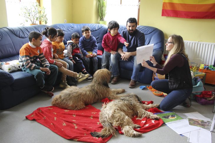 Susanne Rehn (rechts) zeigt auch anhand von Bildern, was man berücksichtigen sollte, damit sich Hund und Mensch verstehen. Ramsi Ali (2.v.r.) hilft mit Übersetzungen.