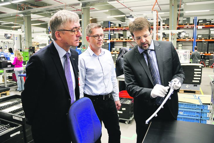 Thomas Meier (rechts), Leiter der Unternehmensentwicklung bei den Bolta Werken, zeigt bei einer Führung durch das Modulcenter 1 Joachim Ossmann, Vorsitzender der Geschäftsführung der Agentur für Arbeit Nürnberg, ein Bauteil. In der Mitte ist Jürgen Harrer, Leiter des Modulcenters.
