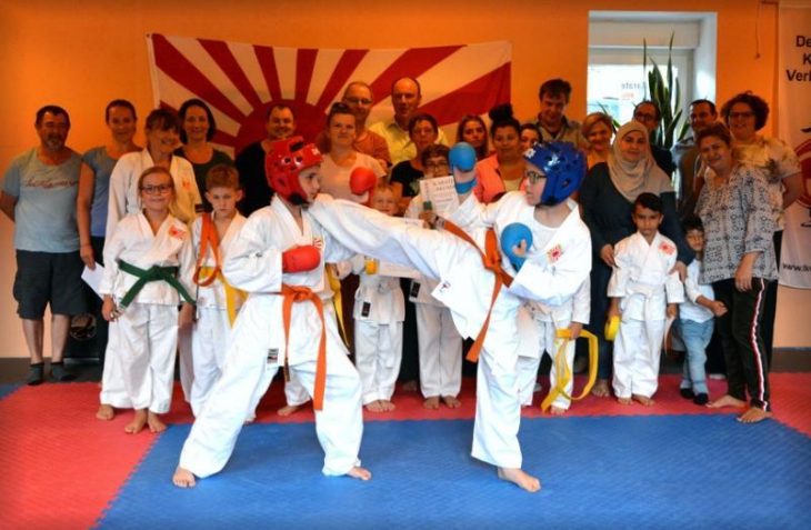 Beim Gruppenfoto nach den Karate-Prüfungen zeigen Martin Pallapies und Felix Nürnberger (rechts) in Schutzausrüstung einen Halbkreistritt.