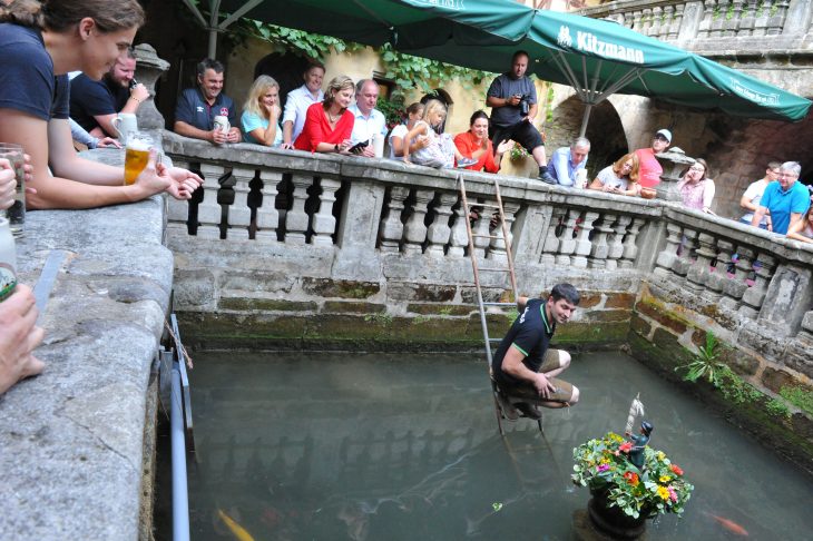 Wirt Markus Haas platziert das „Rockenmännla“ im Wirtshausbrunnen.