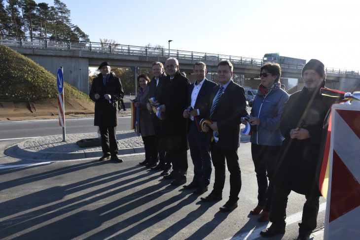 Politiker und Mitarbeiter des Staatlichen Bauamts bei der offiziellen Eröffnung des höhenfreien Knotenpunkts bei Ottensoos. Im Hintergrund verläuft die B14 auf einer Brücke über einen Kreisverkehr.