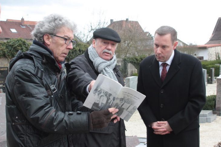 Am Alten Friedhof zeigte Rudolf Höllenreiner (Mitte), ein Angehöriger der früheren Hersbrucker Sinti-Familie Höllenreiner, Landrat Armin Kroder Bilder seiner Vorfahren, die 1943 von den Nazis ins KZ verschleppt wurden. Die Fotos sind im Buch „Verfolgt, deportiert, ermordet“ von Paul Kornmayer (links) zu sehen.
