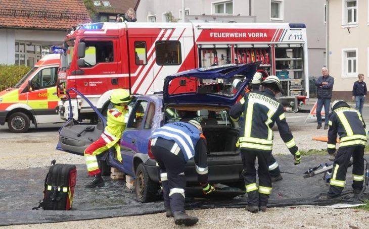 Teamwork: Ein Sanitäter des ASB kümmert sich um den verletzten Fahrer, während sich die Feuerwehrleute über die Heckklappe einen Zugang ins Autoinnere verschaffen.