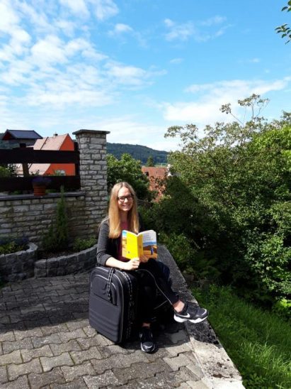 Laura Hentsch sitzt schon auf gepackten Koffern, mit dem Arabisch-Lernbuch in der Hand.
