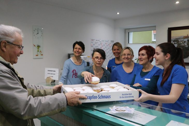 Dieter Bärmann (links) übergibt die Krapfen an die Mitarbeiter der Praxis Kiefer/Stift in Neuhaus.