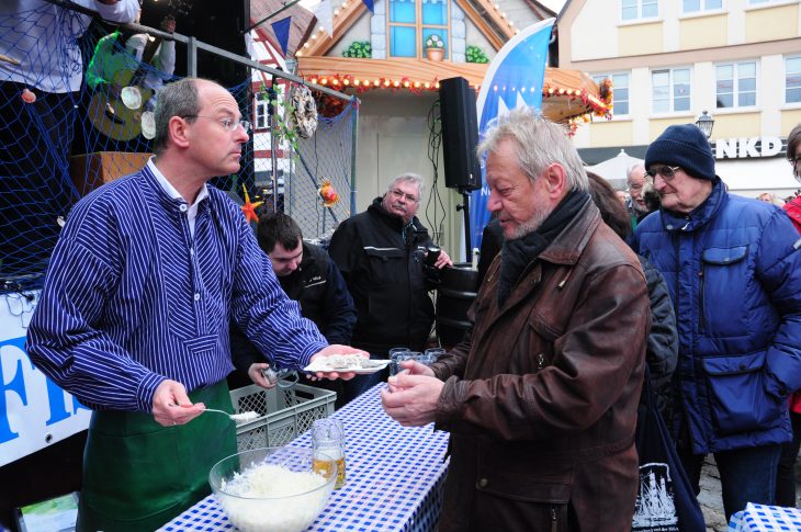 Kann auch Fisch verkaufen: Laufs Bürgermeister Benedikt Bisping reicht den Hering über den Tresen.