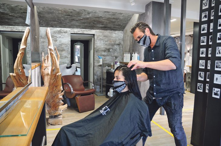 Mit Mundschutz schneidet Friseur Florian Markus in seinem Schwaiger Salon einer Kundin die Haare.