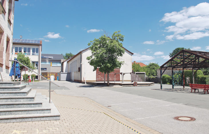 Auf dem Pausenhof der Schnaittacher Grundschule soll ein Hort entstehen. Vermutlich muss dafür die sanierungsbedürftige kleine Turnhalle weichen (das Gebäude in der Bildmitte, links daneben im Hintergrund die neue Turnhalle).