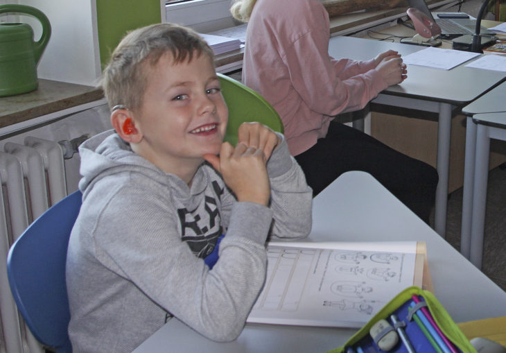 Erste Klasse - da haben die Kinder richtig Freude in der Schule, auch Justus, dessen Hörgeräte drahtlos mit dem Mikrofon seiner Lehrerin verbunden sind. Den Unterricht für den Sechsjährigen möglich gemacht hat eine Akustiksanierung des Klassenzimmers.