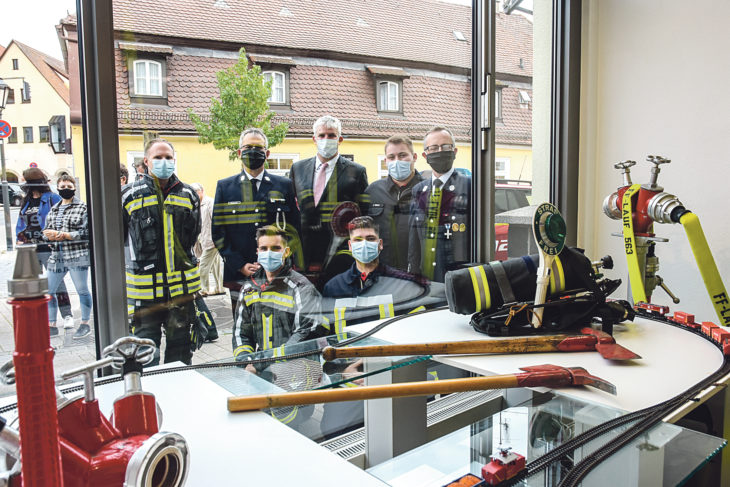 Das „Aktionsteam“ der Feuerwehr Lauf und Bürgermeister Thomas Lang stehen vor dem Schaufenster des Herrenhauses Engelhardt und Walter. Dort dreht sich die Ausstellung rund um das Thema „Lebensretter“.