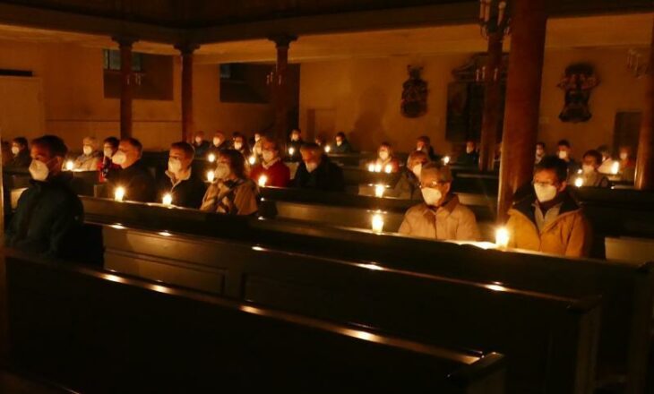 Nur Kerzen spenden zu Beginn der Osternacht im dunklen Kirchenschiff ihr Licht.