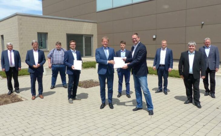 Arnd Stephan übergibt Achim Saßmannshausen das Bahnstrom-Gutachten für Nordostbayern, dahinter das Begleitgremium mit Abgeordneten, Kritikern und Experten aus der Region.