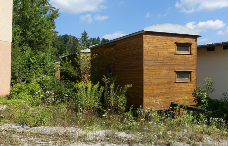 Im Steinbruch zwischen alten Gebäuden und bereits eingewachsen: die zwischengeparkten Bau(Wohn-)wagen.