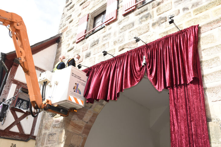 Wie „der Eingang in ein Theater“ soll der Samtvorhang laut Künstler Markus Stirn auf die Besucher der Laufer Lichternächte wirken. Am Mittwoch hängten Stirn (rechts) und sein Team den purpurnen Stoff am Hersbrucker Tor auf. Dort ist er bis zum 3. Oktober Teil der Ausstellung im Freien.