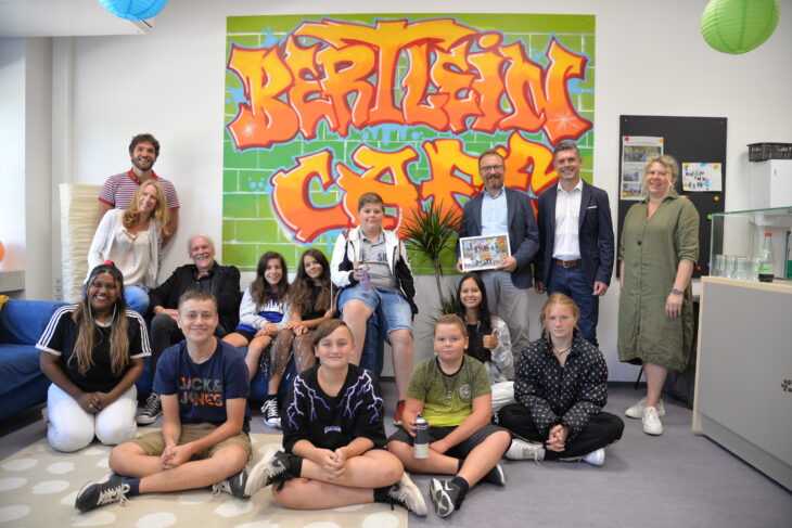 Das Bild  zeigt die beteiligten Schüler sowie Schulleiter Roger Brix (in schwarz, auf der Couch), Kunstlehrer Michael Ziebell (links), Jugendsozialarbeiterin Lea Grabbe (links), Stefan Müller, den Leiter des Fachbereichs Familie und Bildung im Rathaus (2. von rechts), Otfried Bürger (3. von rechts) von der Sparkasse Nürnberg sowie die pädagogische Fachkraft Claudia Gentler (rechts), die im Schülercafé arbeitet.