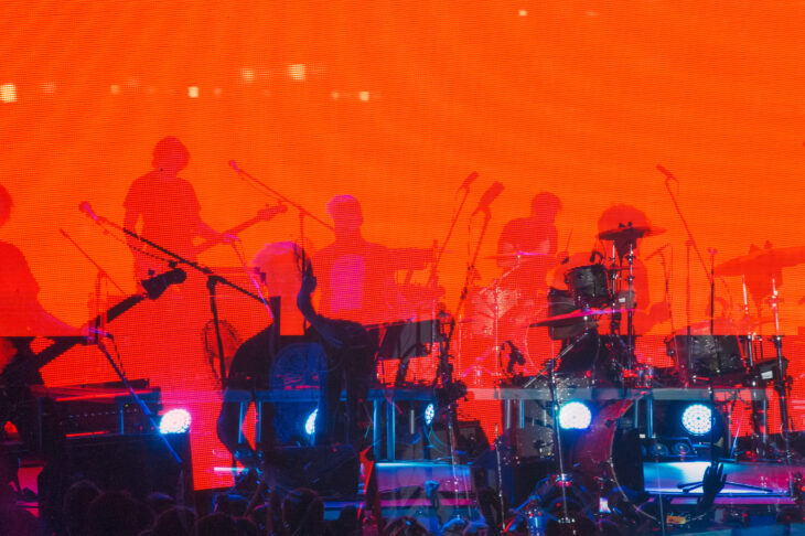 Blurred Background, Musical Rock Band Performs On Stage In The Light Of Spotlights, Rock Music Night Concert. Photo for Design.