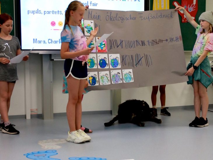 Schülerinnen der 4. Klasse präsentieren ihre Ergebnisse zur Berechnung des ökologischen Fußabdrucks.