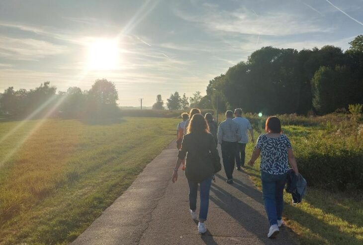 Menschen verschiedenen Alters und unterschiedlicher Hintergründe gehen gemeinsam spazieren und reden dabei miteinander.