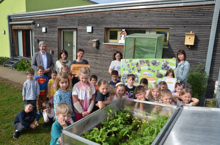 Bürgermeister Robert Ilg, die stellvertretende Geschäftsleiterin Birgit Meister und Heb-i-Kids-Leiterin Christa Seibold (hinten v. links) freuen sich mit den Erzieherinnen und den Kindern über die Auszeichnung „Kita im Aufbruch“ für die städtische Kindertageseinrichtung in der Raiffeisenstraße.