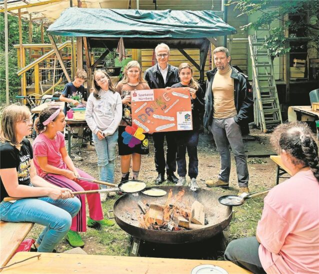 Sascha Makill, Spielplatzleiter Kinderhaus (rechts) freut sich mit den Kindern über die Spende der Sparkasse Nürnberg, vertreten durch Michael Kläver als stellvertretendes Vorstandsmitglied.