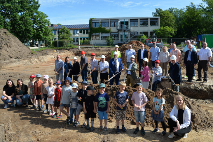 Der symbolische Spatenstich mit Vertretern der Laufer Politik, des ASB Nürnberger Land und des Rathauses sowie Kita-Kindern aus Heuchling auf der Baustelle. Im Hintergrund ist die Heuchlinger Grundschule zu erkennen.