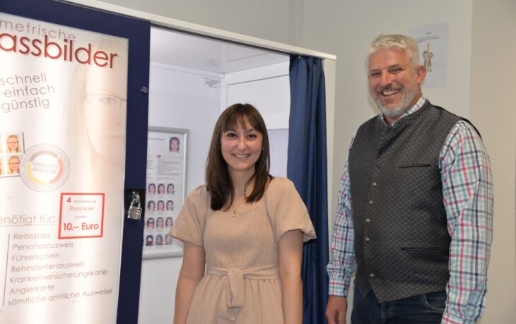 Bürgermeister Thomas Lang und Anna Doms vom Einwohner- und Passamt vor dem neuen Passbildautomaten im Bürgerbüro.