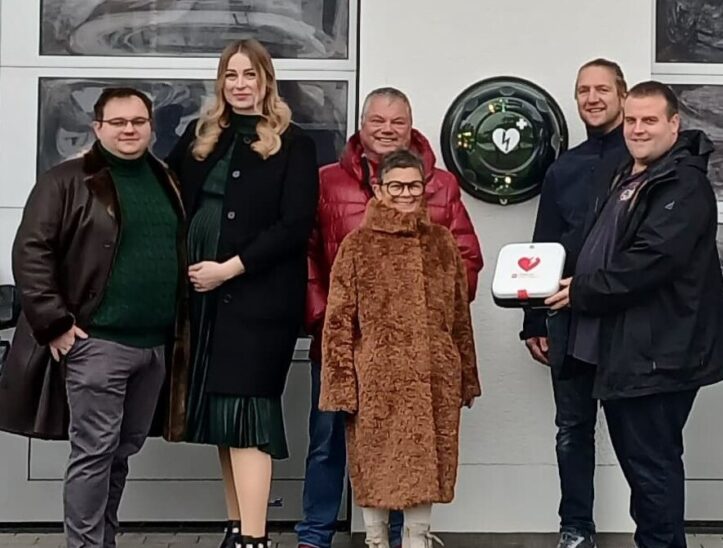 Projektverantwortlicher Matthias Raum, Feuerwehr-Vorstand Christian Zitzmann, sowie Familie Weiser bei der Übergabe des AEDs (von rechts).