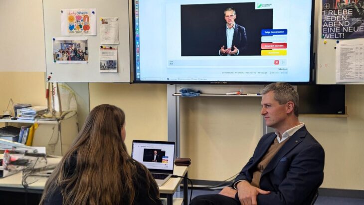 Eine Schülerin der M10b hält vor Paul Dölle (Universität Bayreuth) und dem KI-Avatar eine Präsentation.