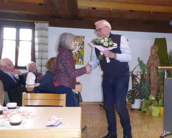 Kirchenpfleger Wolfgang Würker übergibt der Leiterin des Pfarrseniorenkreises Marianne Rochholz zum Jubiläum einen Blumenstrauß.