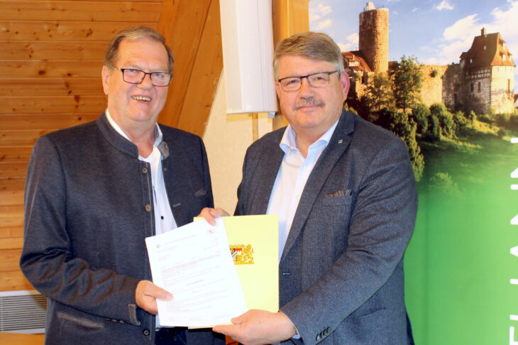 Wolfgang Neukirchner (rechts) überreicht Burgthanns Bürgermeister Heinz Meyer einen Förderbescheid über rund 505.000 Euro.