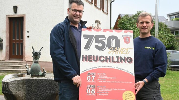 Stellvertretend für die drei Vereine, die das Jubiläumsfest in Heuchling organisieren, halten Kommandant der Heuchlinger Feuerwehr Andreas Stecher (links) und Vorsitzender Timo Keller (rechts) das Plakat vor dem ehemaligen Rathaus hoch.