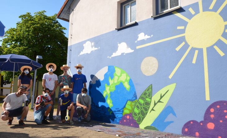 Alex Feer (vorne links) mit den Sprayern der Klasse 8a vor einem Teil ihres farbenfrohen Street-Art-Bildes an der Kindertagesstätte im Haus der Begegnung.