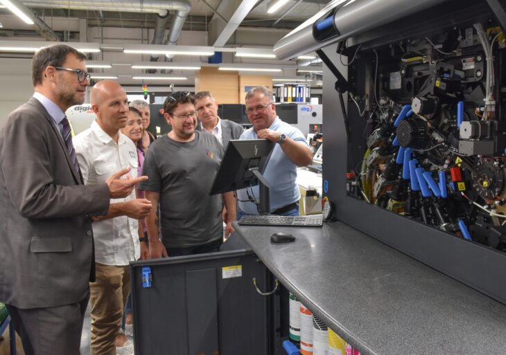 Ralf Kempa (rechts) erklärt den Besuchern die Funktionsweise einer Digitaldruckmaschine.