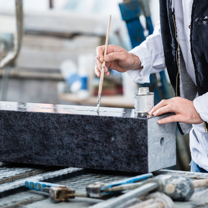stonemason-painting-in-engraving-with-silver-paint