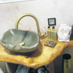 Auf dem Foto sieht man ein kunstvoll gestaltetes Waschbecken auf einem geformten Tisch aus Holz.