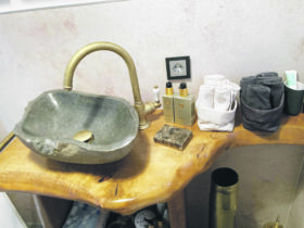 Auf dem Foto sieht man ein kunstvoll gestaltetes Waschbecken auf einem geformten Tisch aus Holz.