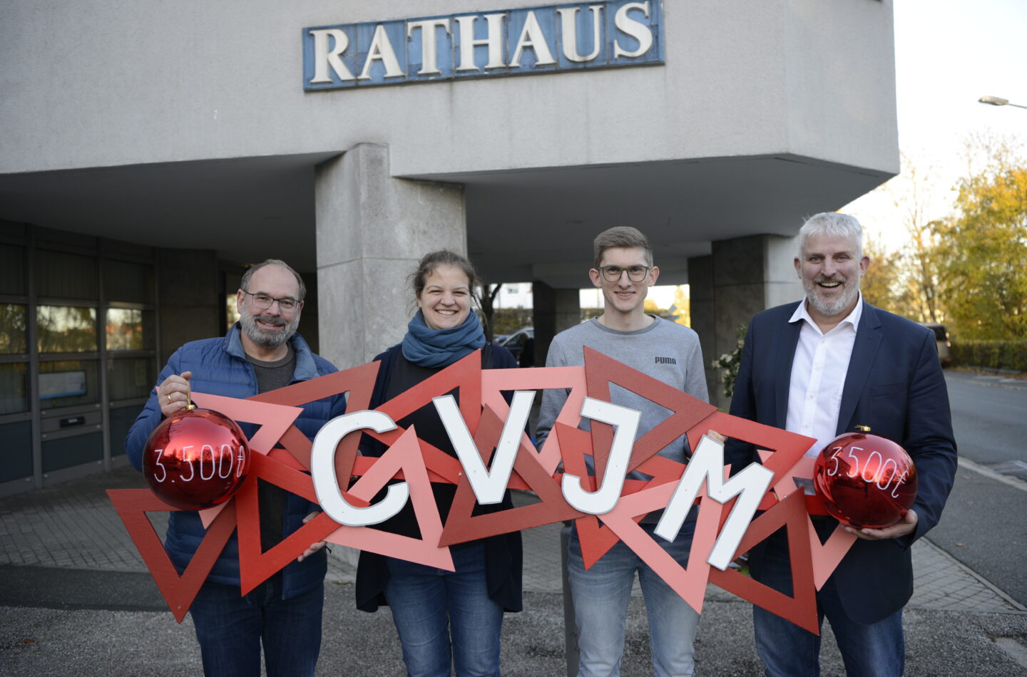 Pfarrer Jan-Peter Hanstein, Anna Eckert vom CVJM, Tobias Kempf, Vorsitzender des Laufer CVJM, und Bürgermeister Thomas Lang (von links) bei der Spendenübergabe vor dem Laufer Rathaus.