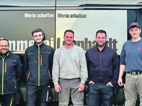 Fünf Mitarbeiter der Firma Zimmerei Leonhardt aus Altdorf zeigen sich vor ihrem Firmenlogo