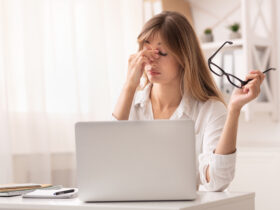 Auf dem Foto sieht man eine Frau vor einem Laptop die sich die Augen reibt