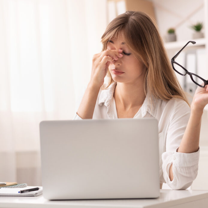 Auf dem Foto sieht man eine Frau vor einem Laptop die sich die Augen reibt