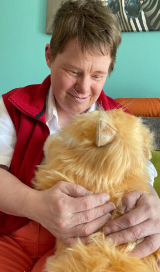 Seniorin Heike Neumann zeigt erste Anzeichen von Demenz. Beim Kuscheln mit KI-Katze Minka hebt sich ihr Gemütszustand merklich.