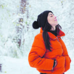 Auf dem Foto sieht man eine Dame in Winterkleidung im winterlichen Wald.