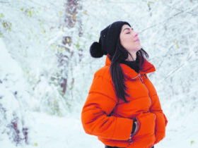 Auf dem Foto sieht man eine Dame in Winterkleidung im winterlichen Wald.