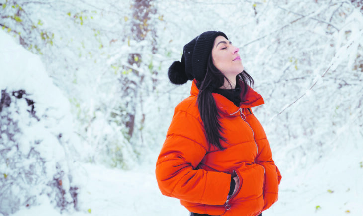 Auf dem Foto sieht man eine Dame in Winterkleidung im winterlichen Wald.
