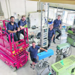 Vier Männer in einem Raum mit Elektrotechnikgeräten